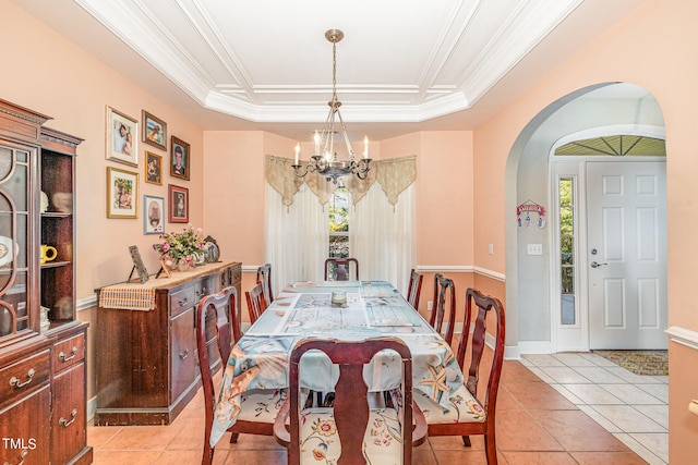 dining space with ornamental molding, a raised ceiling, a notable chandelier, and light tile patterned floors