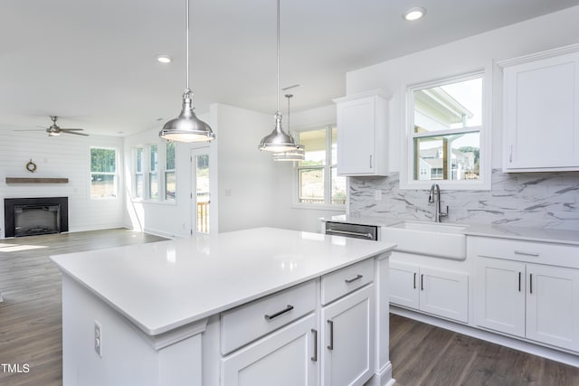 kitchen featuring a sink, tasteful backsplash, white cabinetry, a fireplace, and light countertops