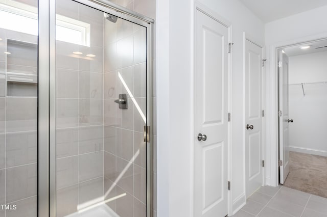 bathroom featuring a shower stall, a spacious closet, and tile patterned floors