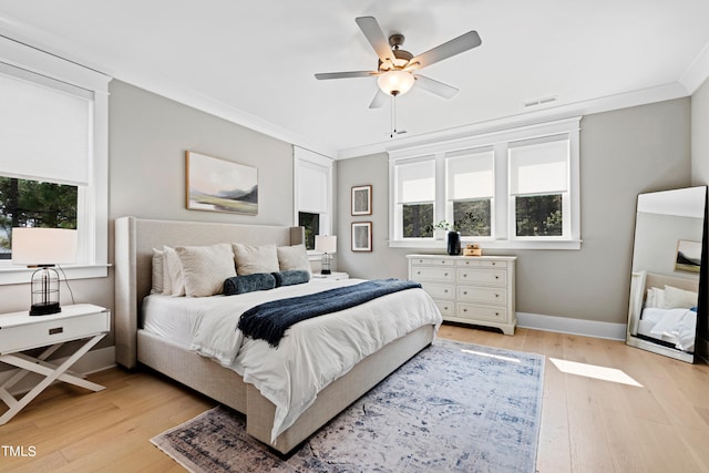 bedroom with light hardwood / wood-style floors, ornamental molding, and ceiling fan