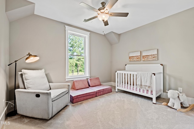 bedroom featuring ceiling fan, carpet flooring, a crib, and vaulted ceiling