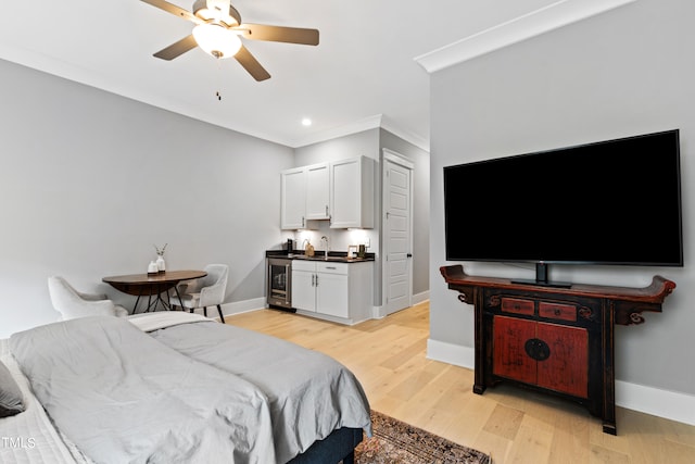 bedroom featuring ceiling fan, sink, beverage cooler, light hardwood / wood-style flooring, and crown molding