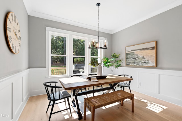 dining room with ornamental molding, light wood-type flooring, and a chandelier