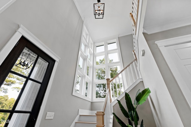 staircase with a towering ceiling and a notable chandelier