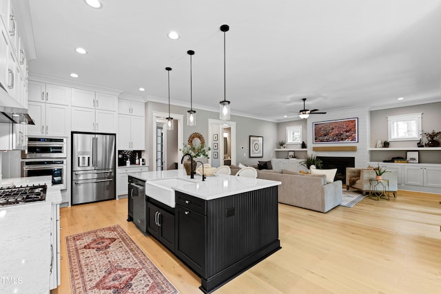 kitchen featuring pendant lighting, white cabinets, sink, a kitchen island with sink, and stainless steel appliances