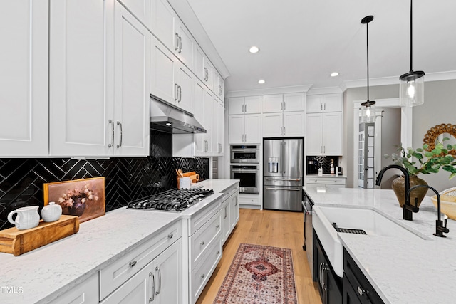 kitchen featuring light wood-type flooring, white cabinetry, stainless steel appliances, decorative light fixtures, and ornamental molding