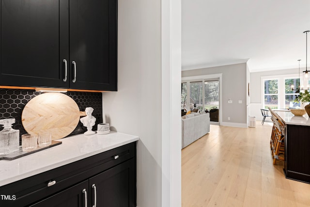 kitchen featuring hanging light fixtures, tasteful backsplash, a chandelier, crown molding, and light hardwood / wood-style floors