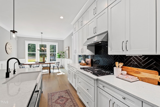 kitchen featuring light hardwood / wood-style floors, white cabinetry, pendant lighting, stainless steel gas stovetop, and sink