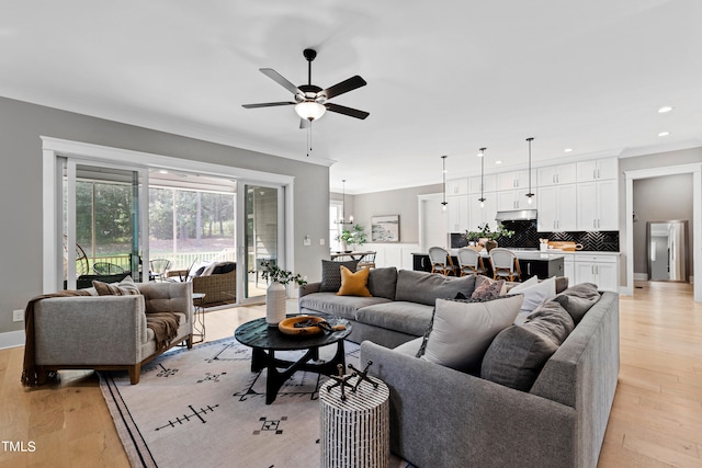 living room with ornamental molding, light hardwood / wood-style floors, and ceiling fan