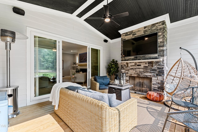 living room with light hardwood / wood-style flooring, lofted ceiling, ceiling fan, and a stone fireplace