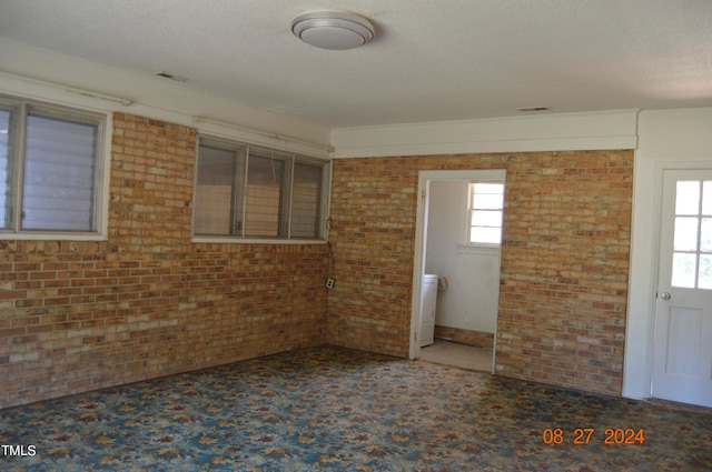 unfurnished room featuring a textured ceiling and brick wall