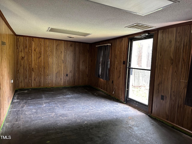 unfurnished room with a textured ceiling and wooden walls