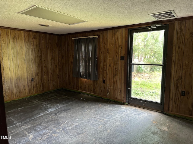 unfurnished room with a textured ceiling and wood walls