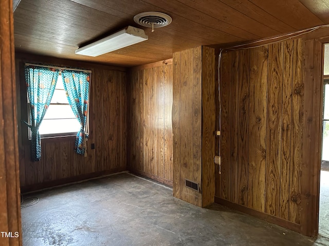 spare room with wooden ceiling, concrete flooring, and wooden walls