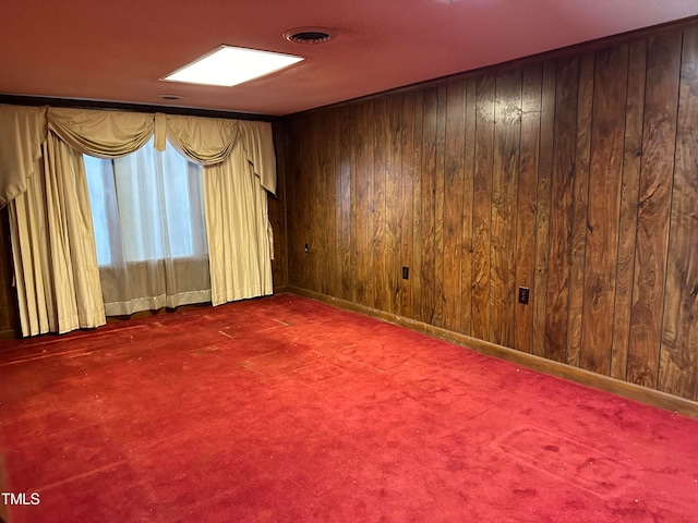 empty room featuring dark carpet and wood walls