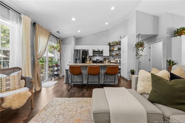 kitchen featuring appliances with stainless steel finishes, white cabinetry, a center island with sink, light stone countertops, and a kitchen bar