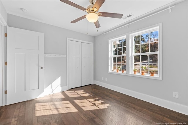 unfurnished bedroom featuring dark wood-type flooring, ceiling fan, and a closet