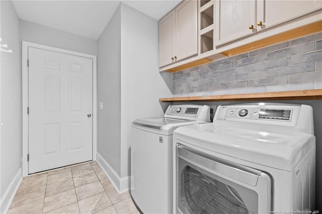 laundry room featuring cabinets, washing machine and dryer, and light tile patterned flooring