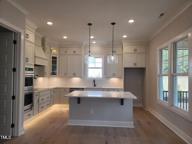 kitchen featuring light countertops, backsplash, a sink, and crown molding