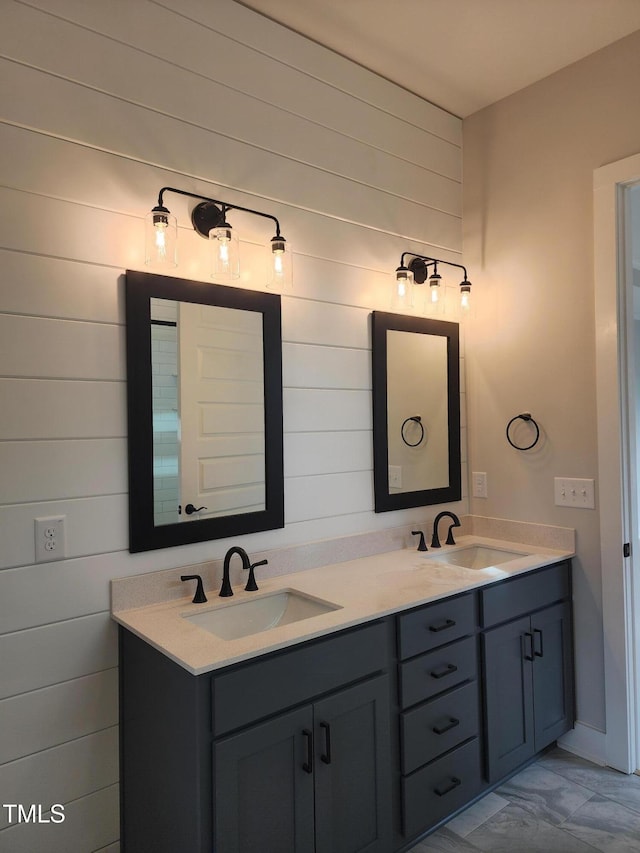 full bathroom featuring double vanity, marble finish floor, wooden walls, and a sink