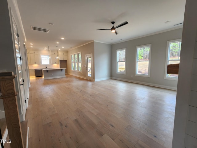 unfurnished living room featuring ornamental molding, plenty of natural light, visible vents, and light wood-style floors