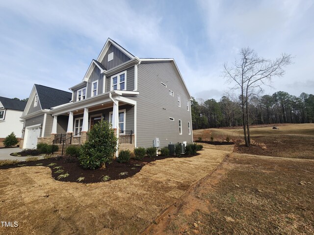 view of property exterior with board and batten siding, covered porch, and a garage