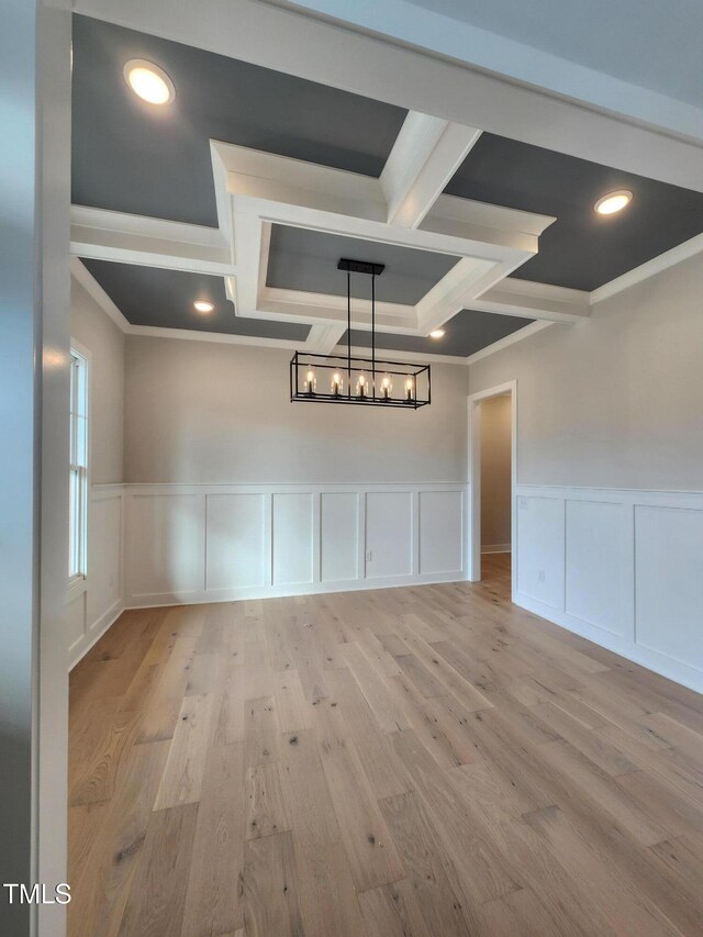 unfurnished room with light wood-type flooring, crown molding, coffered ceiling, and beamed ceiling