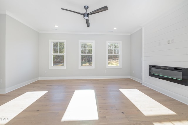 unfurnished living room featuring a large fireplace, crown molding, and a wealth of natural light