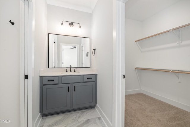 bathroom featuring a walk in closet, vanity, and baseboards