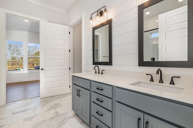 full bath featuring marble finish floor, double vanity, a sink, and crown molding