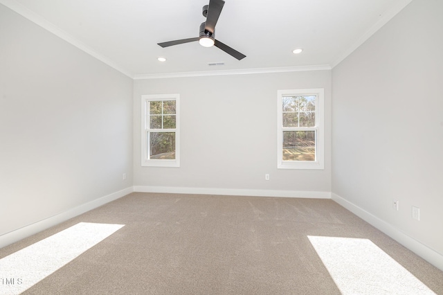 empty room featuring a wealth of natural light, visible vents, and crown molding