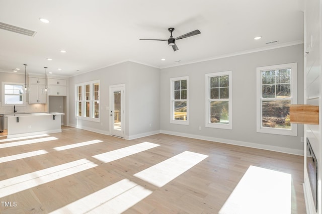 unfurnished living room featuring baseboards, light wood finished floors, visible vents, and crown molding