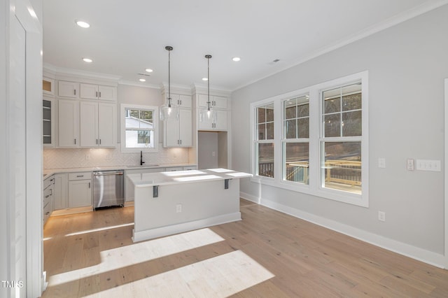 kitchen featuring light wood-style flooring, a sink, backsplash, dishwasher, and crown molding