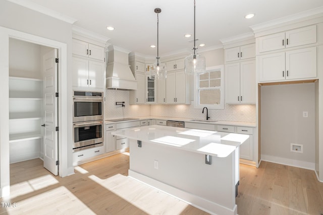 kitchen with stainless steel appliances, light wood finished floors, light countertops, and custom range hood