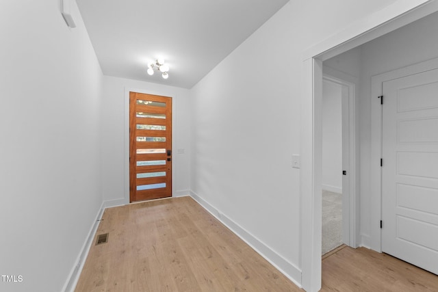 doorway to outside with baseboards, visible vents, and light wood-style floors