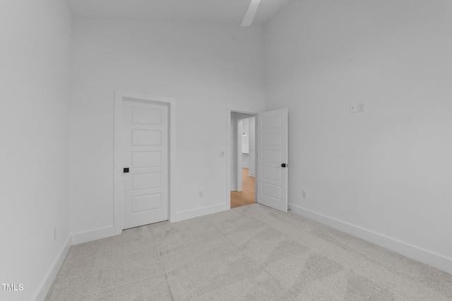 spare room featuring carpet, a high ceiling, and baseboards