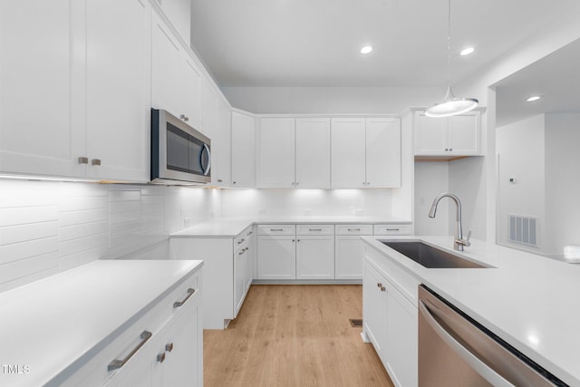 kitchen with a sink, visible vents, white cabinetry, light countertops, and appliances with stainless steel finishes