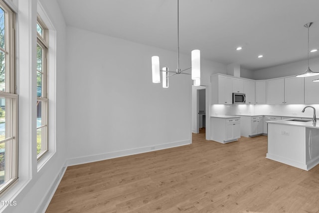 kitchen featuring a wealth of natural light, stainless steel microwave, a sink, and light wood finished floors