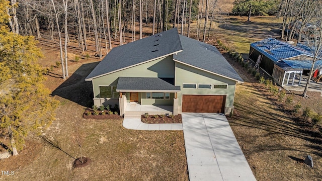 view of front facade featuring a garage, covered porch, driveway, and a shingled roof