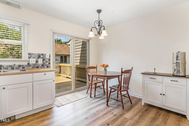 dining area with light wood-type flooring, a notable chandelier, and sink