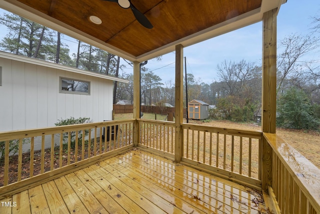 deck with ceiling fan, a storage unit, an outdoor structure, and fence