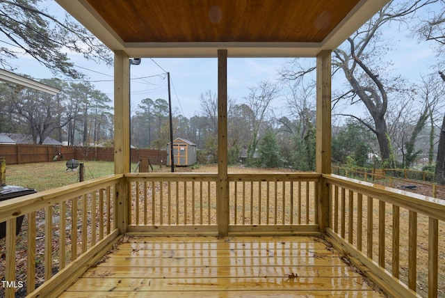 wooden deck with an outbuilding, a storage shed, and a fenced backyard