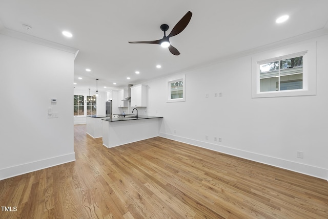 unfurnished living room featuring light wood finished floors, recessed lighting, ornamental molding, a ceiling fan, and a sink