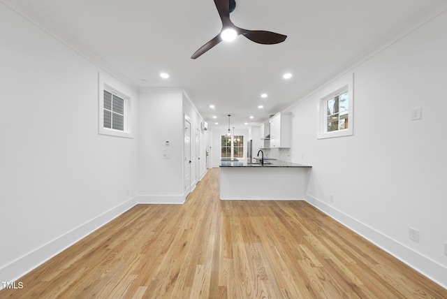 unfurnished living room with light wood finished floors, baseboards, crown molding, and recessed lighting