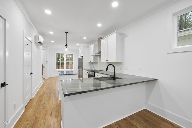 kitchen with tasteful backsplash, light wood-style flooring, a wall mounted air conditioner, a sink, and recessed lighting