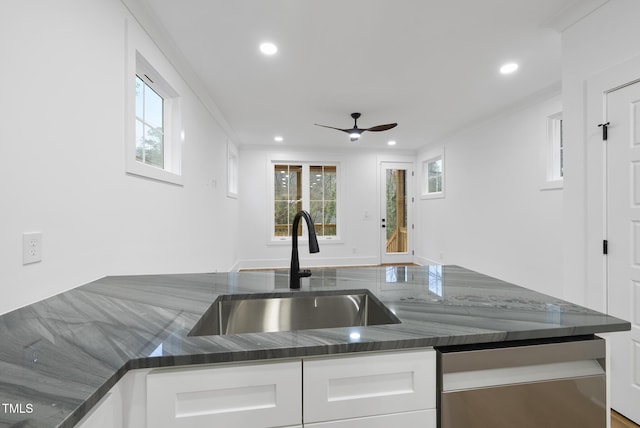 kitchen with crown molding, recessed lighting, white cabinetry, a sink, and dark stone countertops