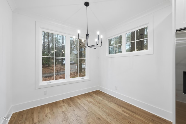 unfurnished dining area with a chandelier, wood finished floors, and baseboards