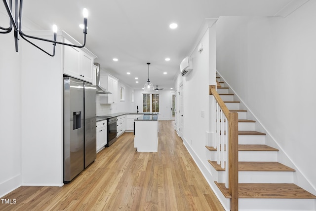 kitchen featuring a wall unit AC, a sink, white cabinetry, stainless steel refrigerator with ice dispenser, and light wood finished floors