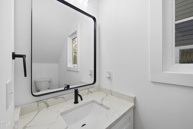 half bathroom featuring toilet, vaulted ceiling, and vanity