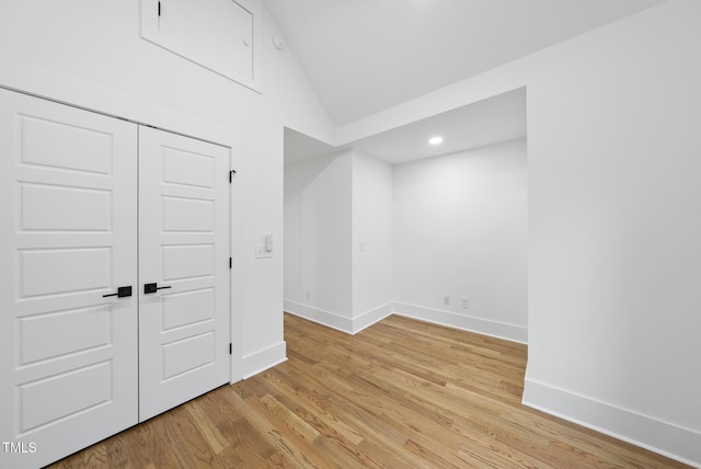 empty room featuring lofted ceiling, light wood finished floors, baseboards, and recessed lighting